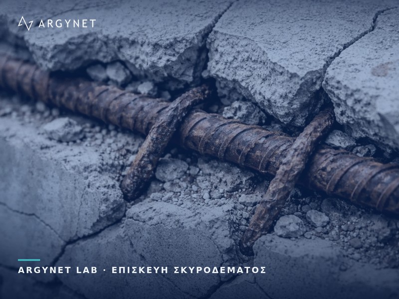 Διαβρωμένη ράβδος οπλισμού και συνδετήρες εκτεθειμένοι μέσα σε ρηγματωμένο σκυρόδεμα που έχει αποκολληθεί